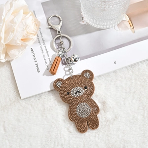 Détail macro du porte-clés ours en strass marron et blanc avec frange et clochette argent
