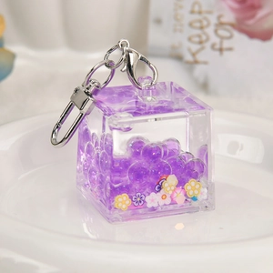 Purple acrylic cube liquid keychain with floating beads and glitter on white plate