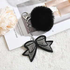 Détail d'un porte-clés à pompon noir avec pendentif nœud orné de strass argentés