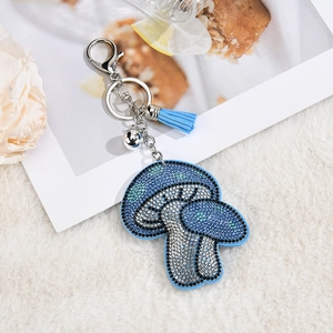 Close-up of blue rhinestone mushroom keychain with silver bell and matching tassel