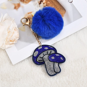 Blue faux fur pompom keychain with a sparkling rhinestone mushroom pendant and gold clasp