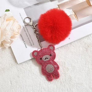 Detail of cute bear keychain with pink rhinestones, red faux fur pompom and silver clasp