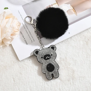 Detail view of a black faux fur pompom keychain with a sparkling rhinestone bear pendant
