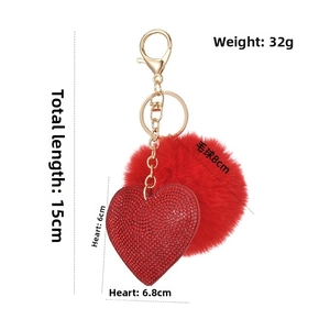 Macro view of 15cm red faux fur pompom keychain with rhinestone heart and gold hook
