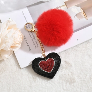 Red faux fur pompom keychain with rhinestone heart charm on a stylish background