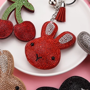Detail of glittery rhinestone bunny and cherry keychains with leather tassels
