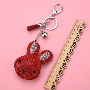 Detail of red rhinestone rabbit keychain with leather tassel and silver bell decoration