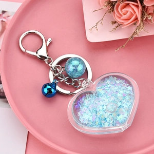 Detail of blue acrylic heart keychain with liquid glitter, metal bell and lobster clasp