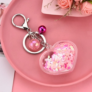 Pink heart-shaped acrylic liquid keychain with glitter, bell, and metal clip for bags