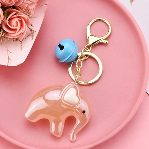 Detail of pink acrylic elephant keychain with a blue bell and golden lobster clasp