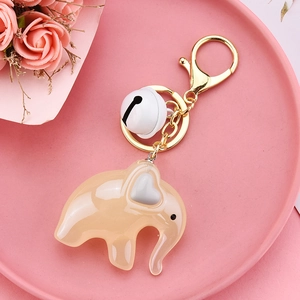 Close-up of champagne acrylic elephant keychain with small white bell and golden lobster clasp