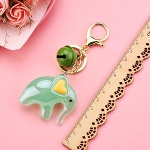Detail of mint green acrylic elephant keychain with yellow heart and green bell accessory