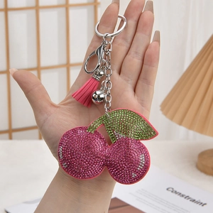 Pink rhinestone cherry keychain with tassel and silver bell held in hand