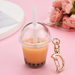 Close-up of a miniature bubble tea keychain with golden D-ring clasp on pink background