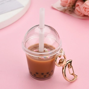 Detail of creative bubble tea keychain with mini straw and golden moon clasp on pink background
