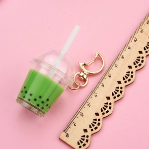 Detail of matcha green bubble tea keychain with moon clasp on pink background