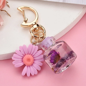 Macro view of flower glass bottle keychain with purple dried petals and daisy pendant