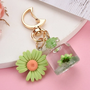 Golden moon keychain with green daisy pendant and clear miniature glass bottle charm