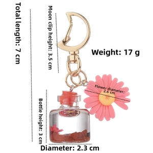 Detailed view of moon clasp keychain with dried flower bottle and pink daisy charm