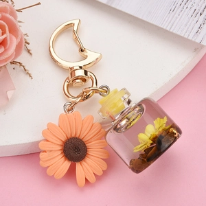 Detail view of sunflower pendant with mini glass bottle and golden moon keychain clasp