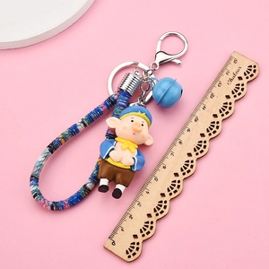 Detail of cartoon pig keychain with blue bell and woven rope, measuring about 13cm