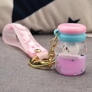 Detail of cute cat oil-filled bottle keychain with pink party wristlet and sequins