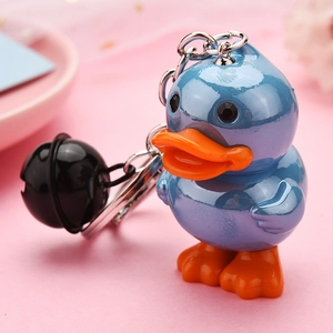 Detail of blue acrylic duck keychain with black bell accessory on pink background