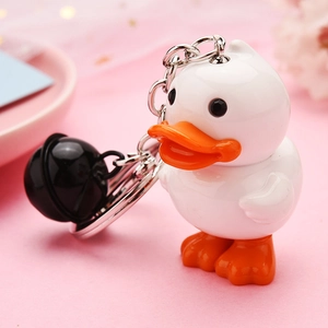 Close-up of cute white duck acrylic keychain with orange beak and black bell charm