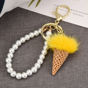 Close-up of creative ice cream keychain with yellow faux fur and pearl handle detail