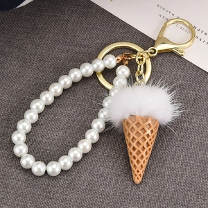 Creative ice cream keychain with white faux fur pompom and pearl ring on grey background