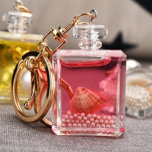 Close-up of a pink perfume bottle keychain with floating pearls and sea shells