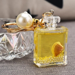 Detail view of perfume bottle keychain with yellow quicksand, pearl and gold clasp