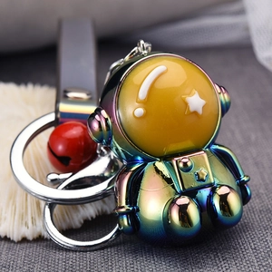 Macro shot of an iridescent astronaut keychain with a red ball and silver ring