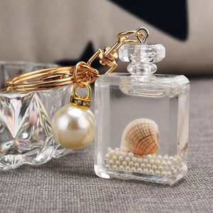 Detail of acrylic perfume bottle keychain with gold hardware, shell, and pearls