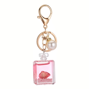 Pink liquid quicksand keychain with shell, white pearl, and acrylic perfume bottle charm