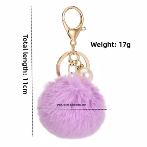 Detail view of purple faux rabbit fur pom pom keychain with gold clasp and pearl bead
