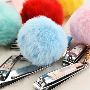 Macro detail of Romantic stainless steel nail clippers with colorful faux fur pom-poms