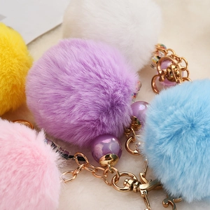 Detail of colorful faux fur pompom keychains with golden heart clasps and purple beads