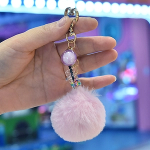 Detailed shot of pink faux fur pompom keychain with gold heart clasp and sequin bottle