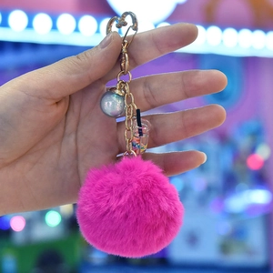 Close-up of rose pink faux fur pompom keychain with heart clasp and boba tea charm
