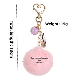 Pink faux fur pompom keychain with golden heart clasp and boba tea charm details