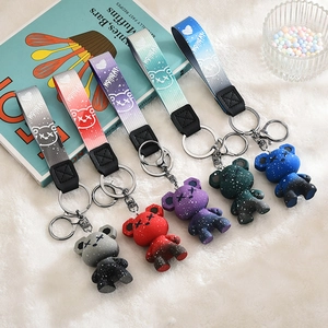 Five galaxy pattern bear keychains with fashion nylon straps on white faux fur background