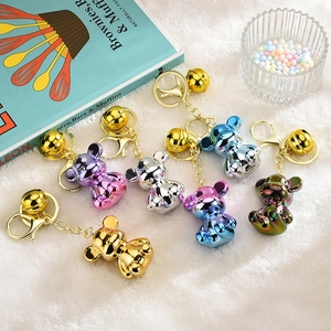Set of six cute colorful electroplated bear keychains with gold bells on white fur background