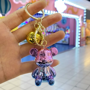 Detail of a purple-blue gradient bear keychain with golden bell and metal clip