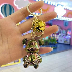 Detailed macro view of an iridescent electroplated bear keychain with a golden bell and ring
