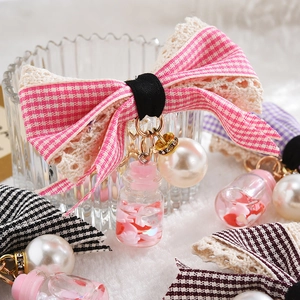 Pink checkered lace bow keychain with pearl and sequin charm on fuzzy white background