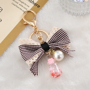 Detailed shot of burgundy houndstooth bow with pearl and lace pendant on a keychain