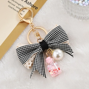 Detail of alloy keychain with bowknot, pearl bead, and pink heart sequin bottle charm