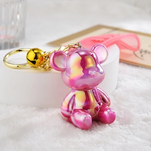 Detailed close-up of a laser gradient bear keychain with golden bell and pink silicone strap