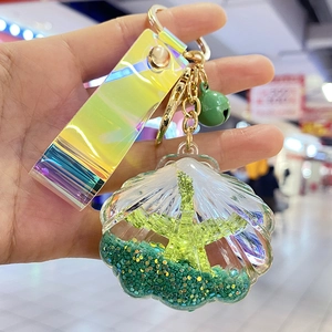 Detail of acrylic shell keychain with seahorse charm, laser strap, and green bell